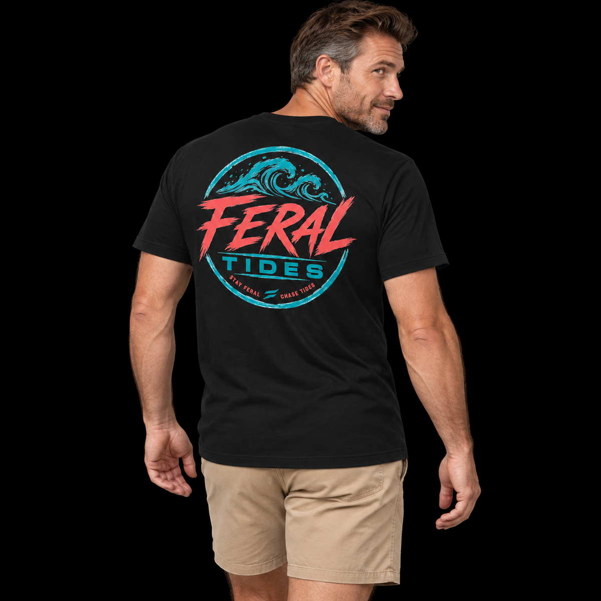 Male model wearing the Black Feral Tides Tidal Rebel Tee, looking back over right shoulder with arms relaxed, showing the large coral-and-teal wave graphic on the back against a solid black background.