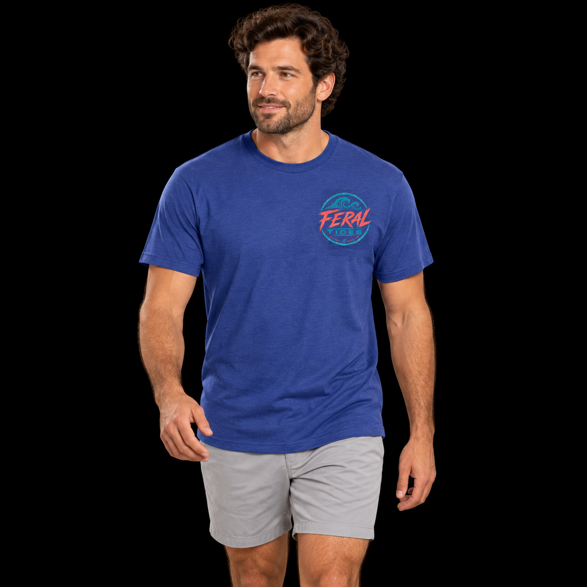 Male model wearing the Deep Blue Feral Tides Tidal Rebel Tee, walking casually and looking left, showing the small coral-and-teal wave logo on the front chest against a solid black background.