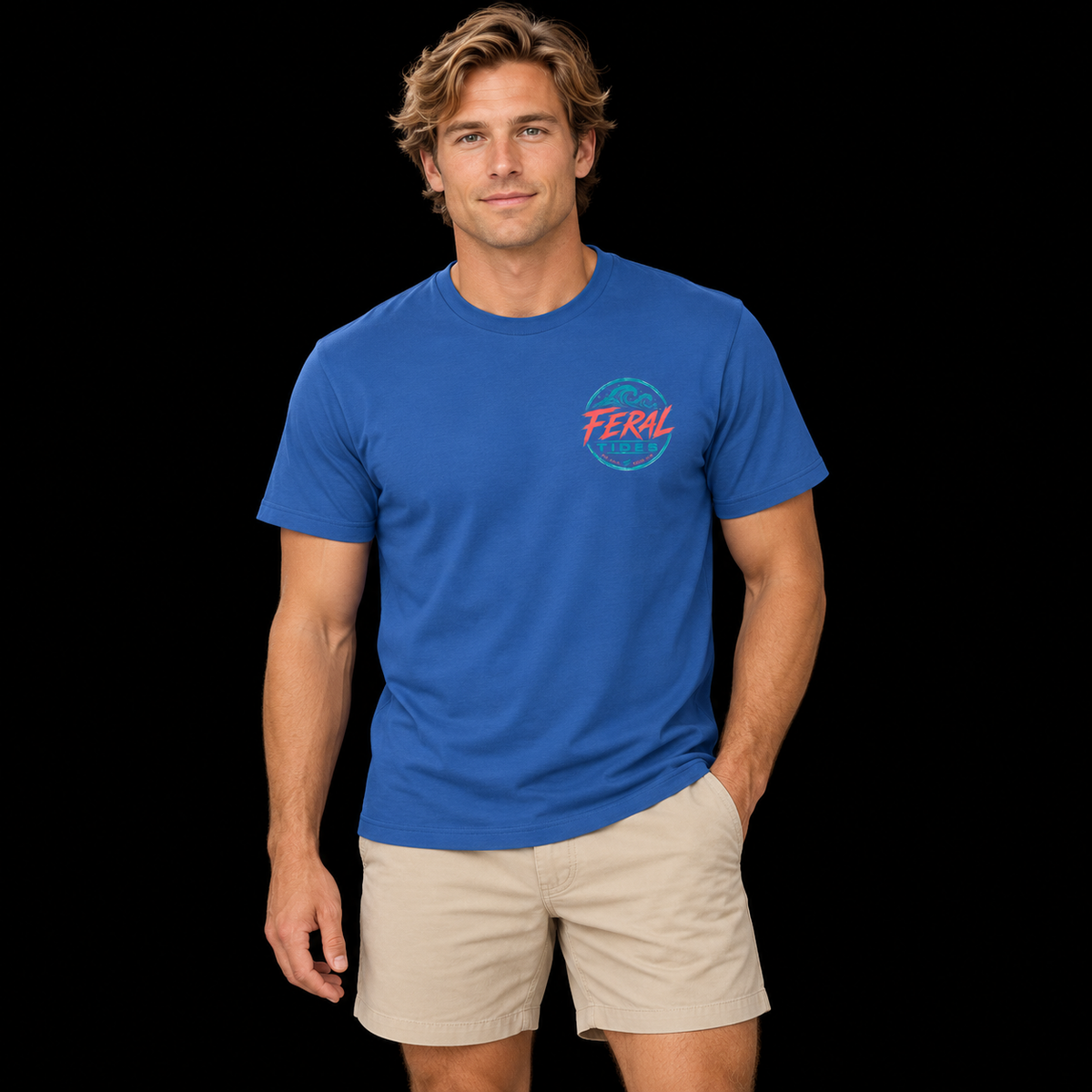 Male model wearing the Royal Feral Tides Tidal Rebel Tee, standing with one hand in pocket and facing the camera, showing the small coral-and-teal wave logo on the front chest against a solid black background.